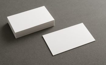 A stack of blank business cards on a gray surface, with one card slightly displaced from the stack.